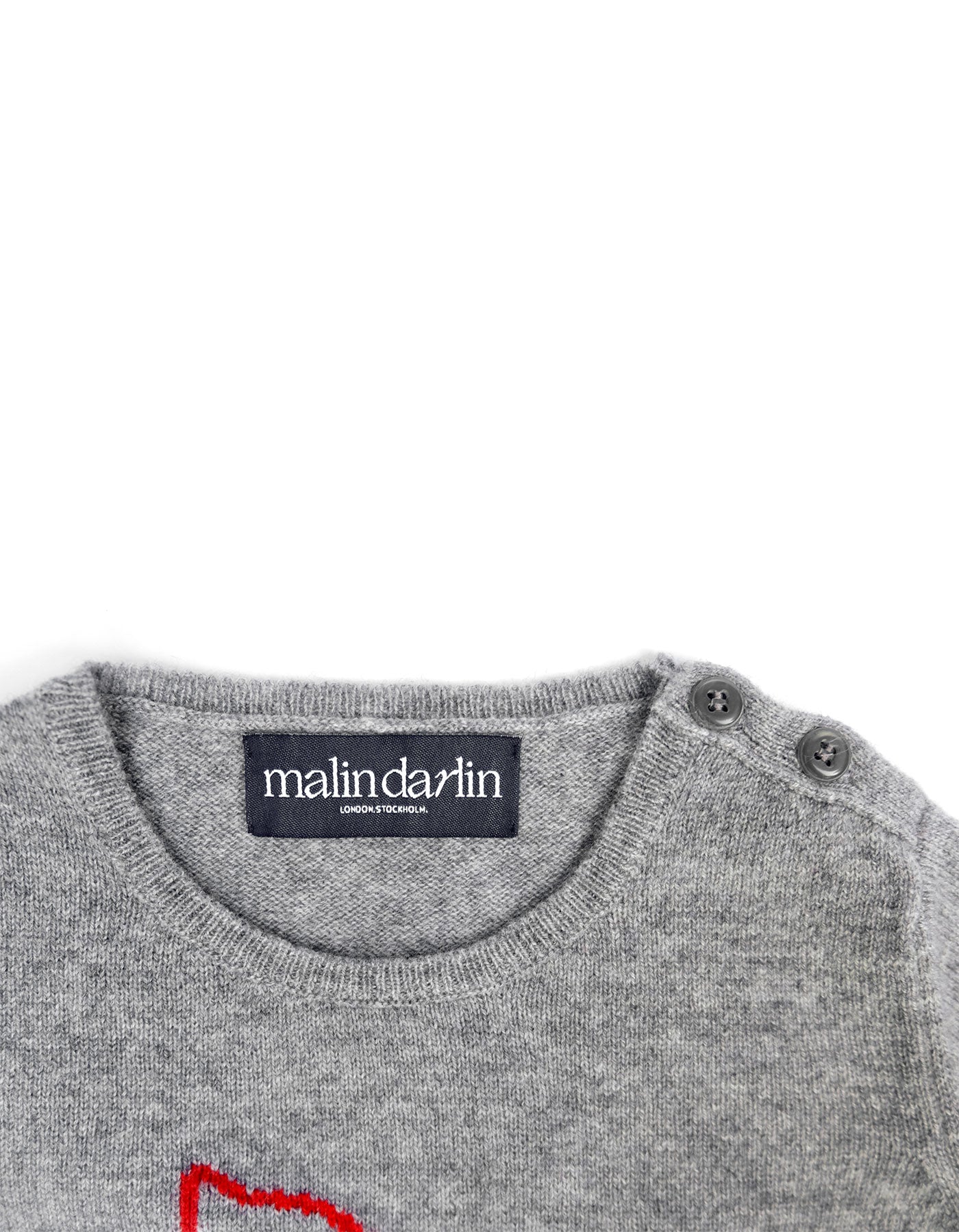 Neck and fastening detail of a kids cashmere jumper showing the knit and label.