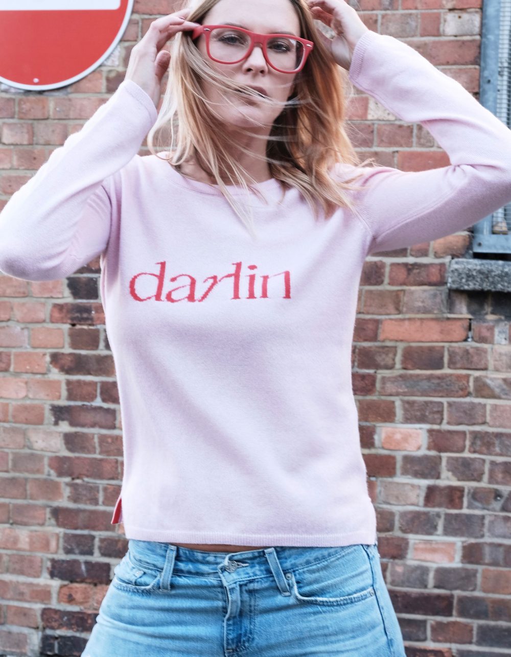 A model with long blonde hair wearing a Darlin Pink cashmere jumper.