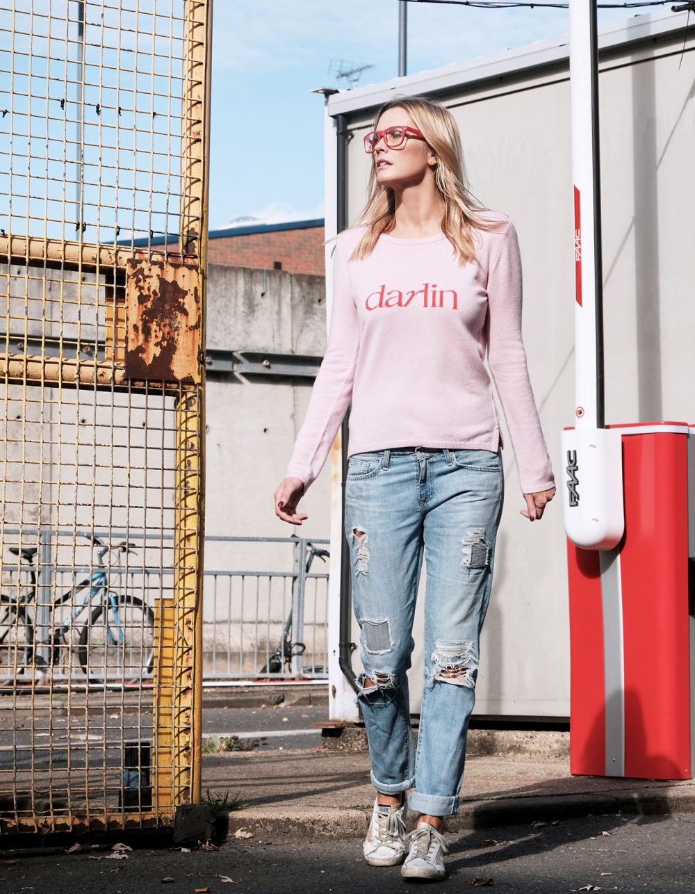 Woman wearing designer knitwear, the Darlin Pink cashmere jumper, pictured in an urban setting.