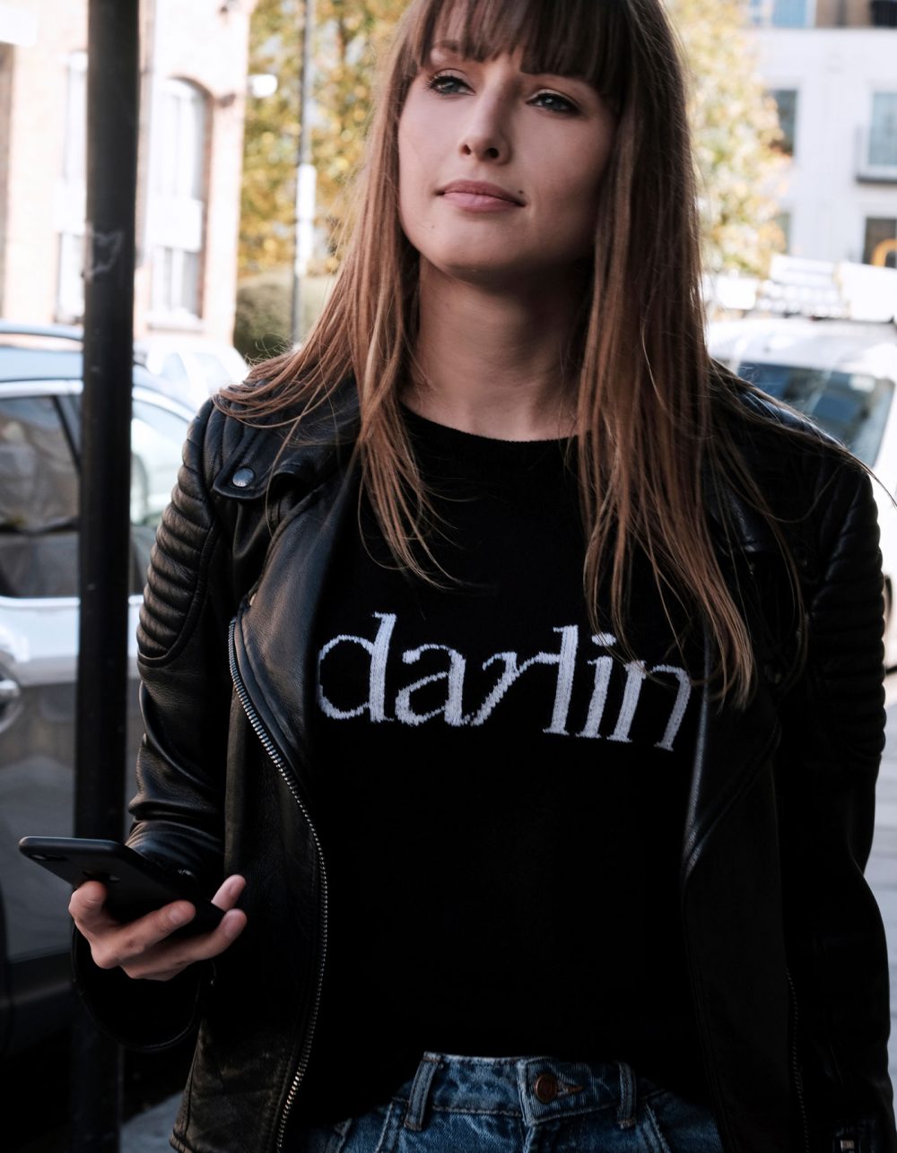 Woman dressed in a Darlin black cashmere jumper and black biker jacket.