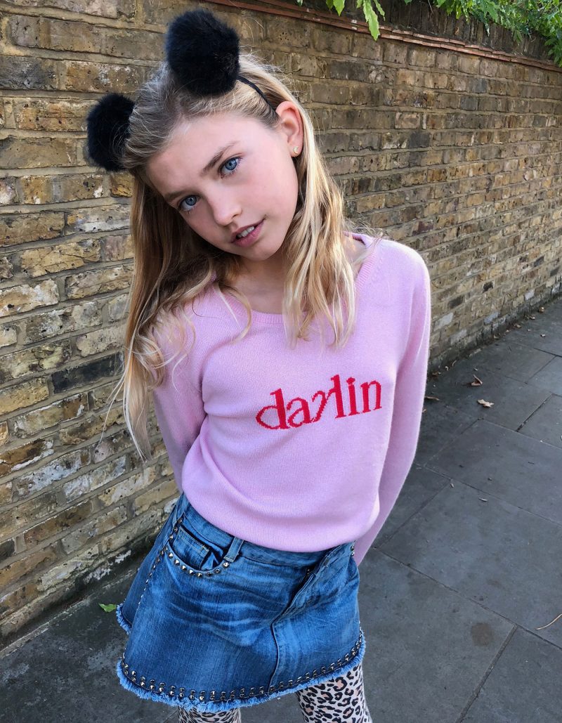 A fashionably dressed girl modelling malin darlin knitwear, a Little Darlin pink kids cashmere jumper.