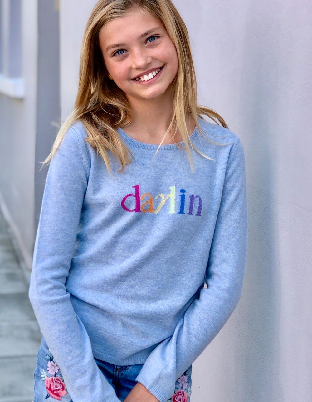 A smiling child in a darlin girl cashmere jumper, one of the signature styles in kids cashmere jumpers at malin darlin.