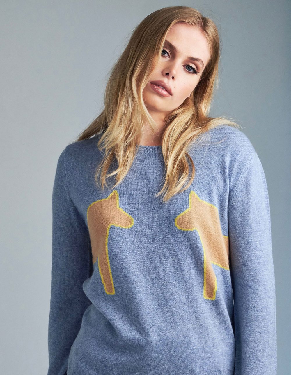 Shot of a model promoting 2 pony blue cashmere jumpers, part of the malin darlin luxury cashmere collection.