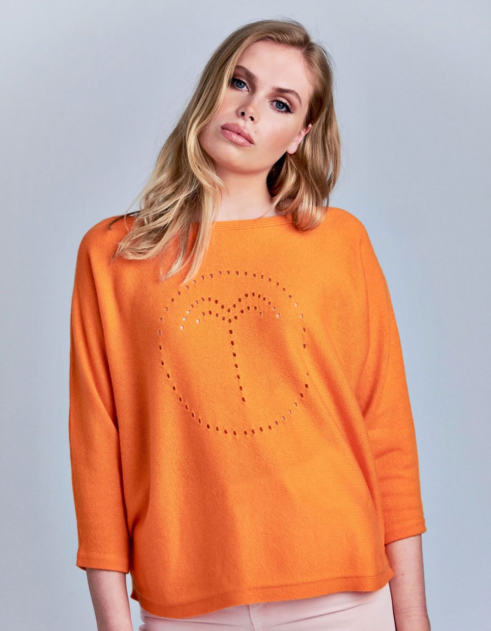 A model wearing the palm jumper in orange, part of the malin darlin range of designer cashmere jumpers.