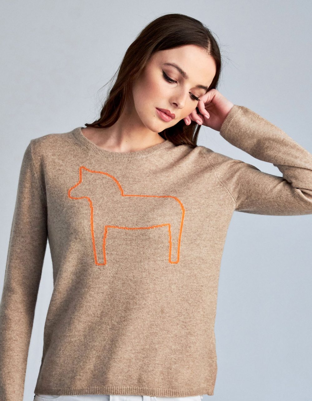 An image of a woman in one of the malin darlin Dalahast horse cashmere jumpers, a pony depicted on beige cashmere.