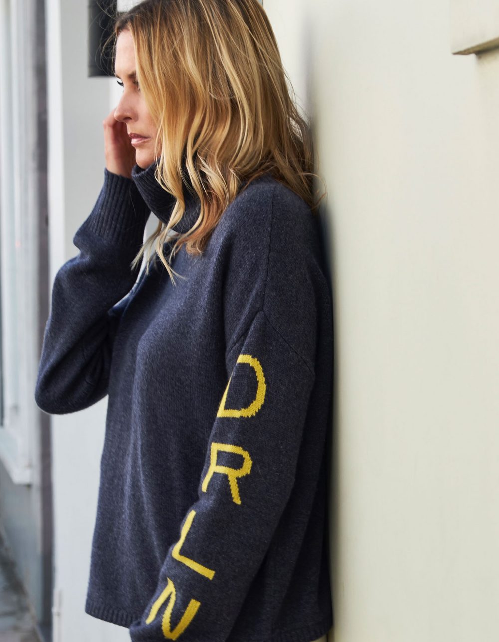 Image of a woman on a quiet street wearing the malin darlin signature DRLN oversized cashmere jumper.