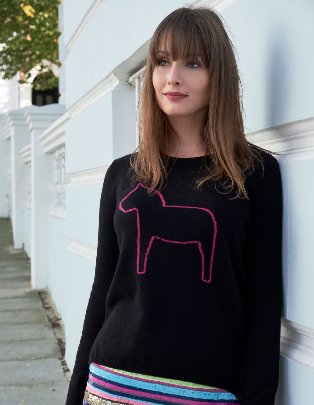 A black cashmere jumper with a pink outline of a Dalahast horse knitted into the design.