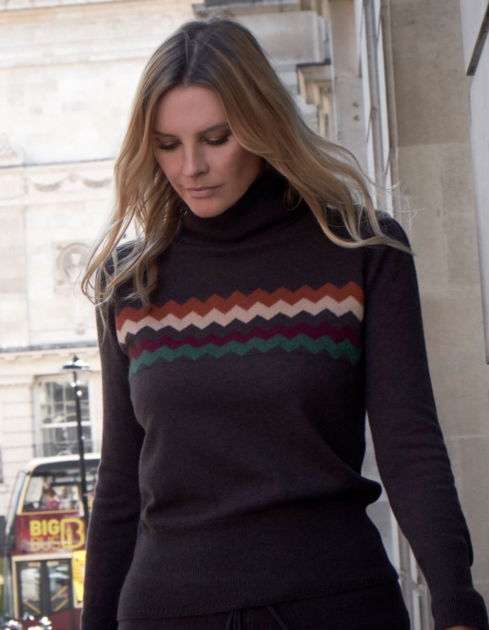 Woman on a busy street wearing malin darlin cashmere knitwear, the Zigzag chocolate cashmere jumper.